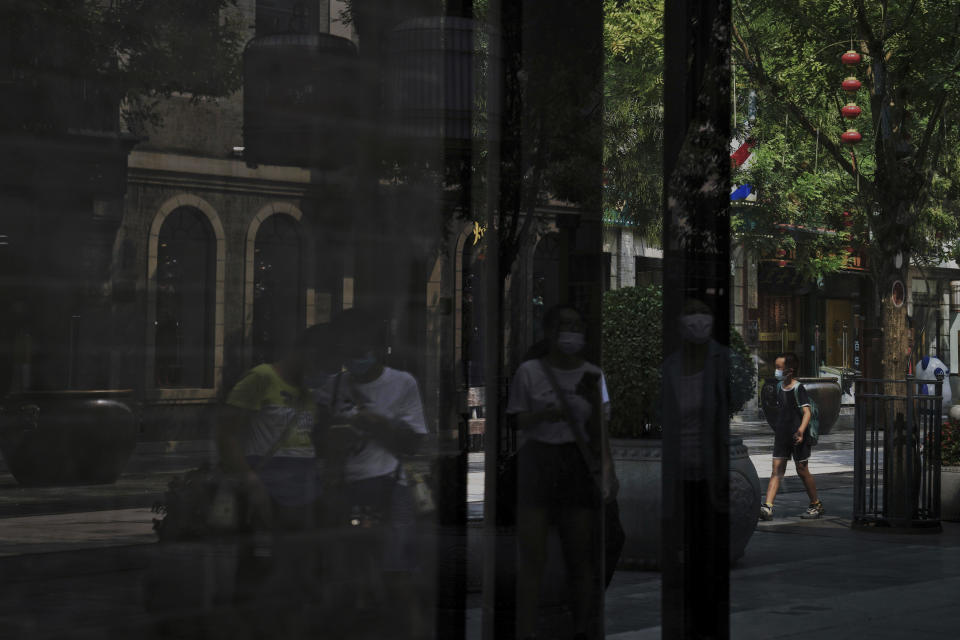 Visitors wearing face masks tour past vacant shop lots at Qianmen Street in Beijing, Wednesday, Aug. 17, 2022. Factories in China's southwest have shut down after reservoirs used to generate hydropower ran low in a worsening drought, adding to economic strains at a time when President Xi Jinping is trying to extend his position in power. (AP Photo/Andy Wong)