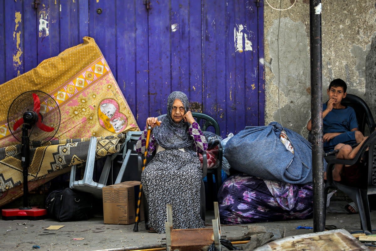 An elderly woman and child wait with belongings before evacuating from Rafah (AFP)