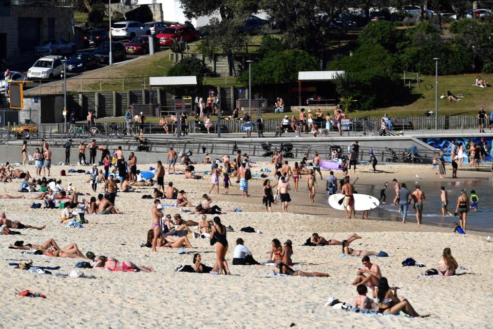 People sit out on Australia’s famous Bondi Beach  (AFP via Getty Images)