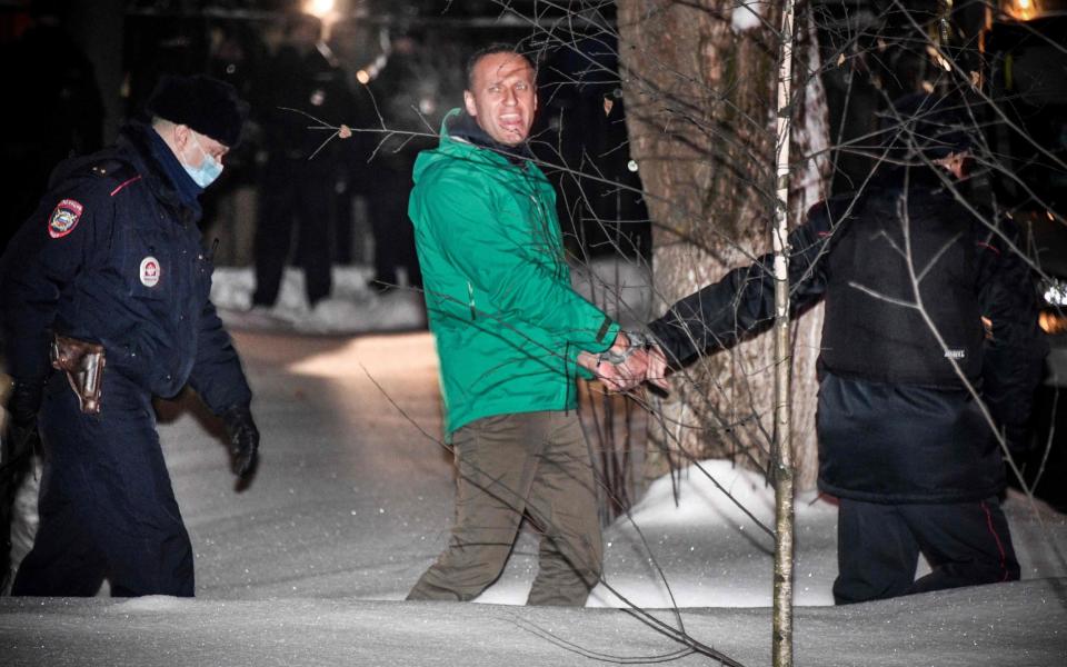 Navalny is escorted out of a police station in Khimki, outside Moscow