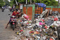 A man throws adds a bag of waste to an open garbage dump in Jakarta, Indonesia, Tuesday, Jan. 25, 2022. Indonesian parliament last week passed the state capital bill into law, giving green light to President Joko Widodo to start a $34 billion construction project this year to move the country's capital from the traffic-clogged, polluted and rapidly sinking Jakarta on the main island of Java to jungle-clad Borneo island amid public skepticism. (AP Photo/Dita Alangkara)