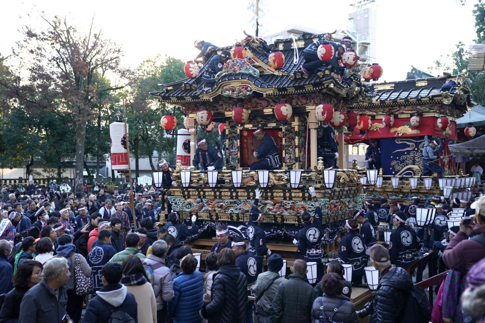 In this Tuesday, Dec. 3, 2019, photo, participants clad in traditional happi coats put lanterns on floats before it goes to the town central square during the Chichibu Night Festival in Chichibu, north of Tokyo, Japan. Moving six towering floats up a hill and into the town center is the culminating moment of a Shinto festival that has evolved from a harvest thanksgiving into a once-a-year meeting between two local gods. (AP Photo/Toru Hanai)