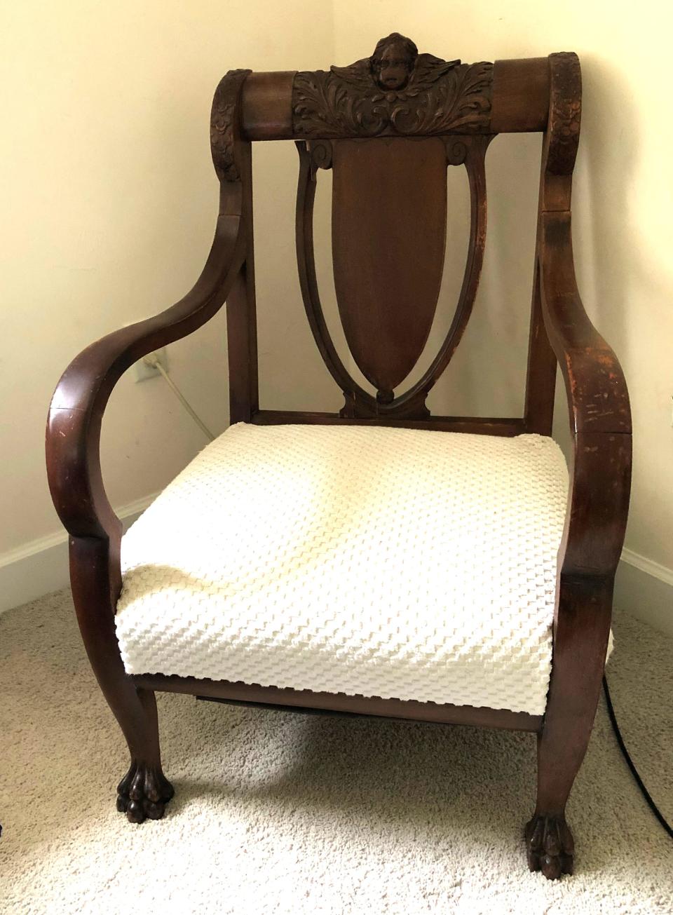 This chair was made in America, possibly in Grand Rapids, Michigan. The style is Empire Revival. The white upholstery is not appropriate for the chair.