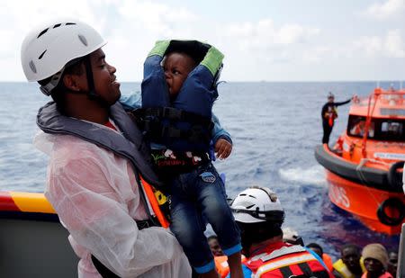 A cultural mediator from Italian NGO EMERGENCY carries a migrant baby on board the Migrant Offshore Aid Station (MOAS) rescue ship Topaz Responder around 20 nautical miles off the coast of Libya, June 23, 2016. REUTERS/Darrin Zammit Lupi