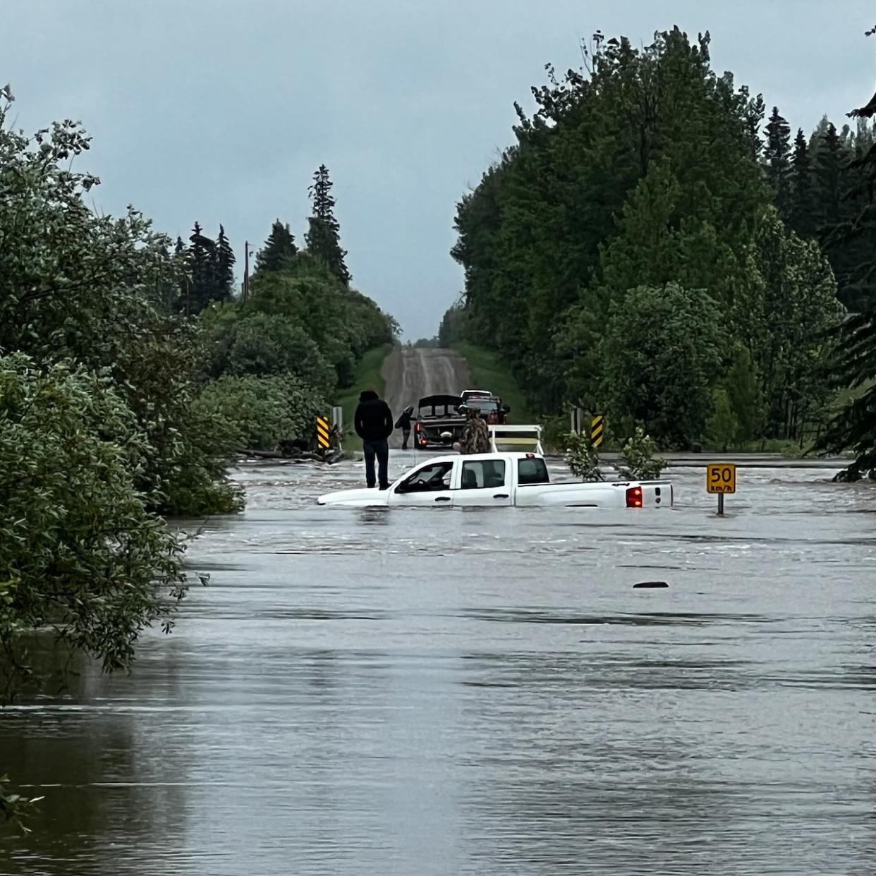 A person stands on top of truck surrounded by floodwaters near Carrot Creek, Alta. Yellowhead County declared a state of local emergency following days of heavy rain in June 2023.  (Yellowhead County/Facebook - image credit)