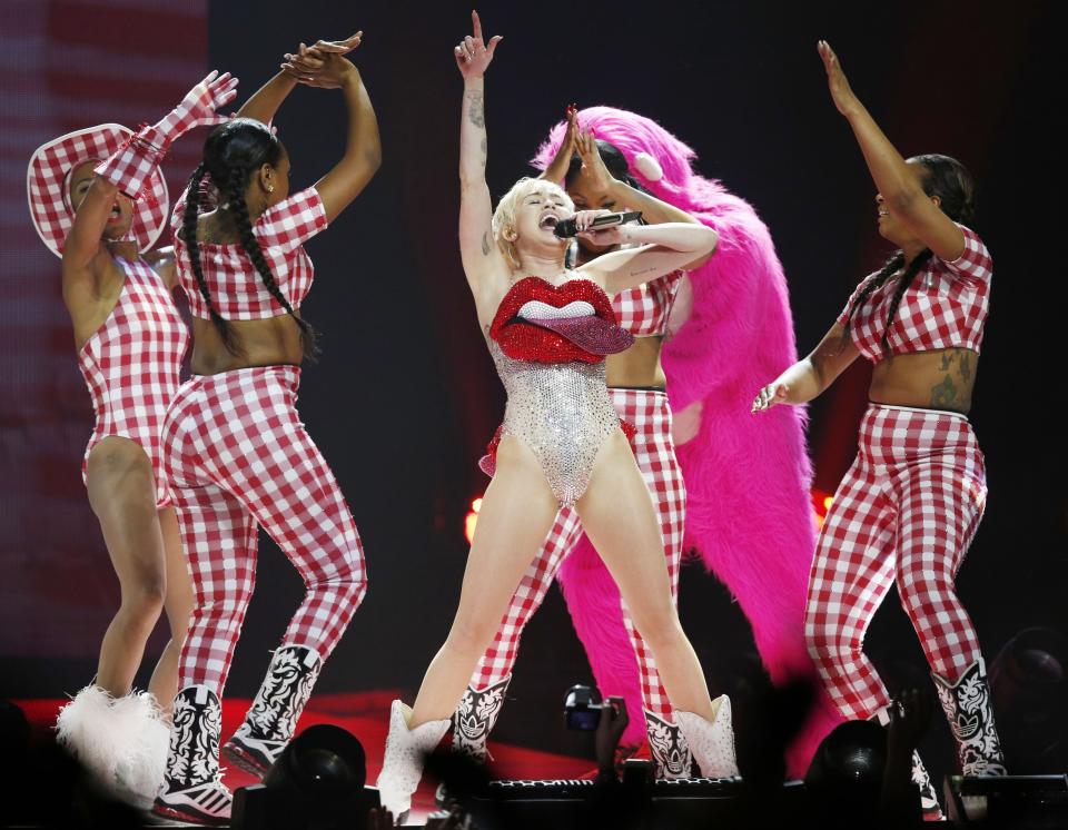 US singer Miley Cyrus, centre performs in concert on the UK leg of her Bangerz tour, at the O2 Arena, London, Tuesday, May 6, 2014. (AP Photo/PA, Jonathan Brady) UNITED KINGDOM OUT