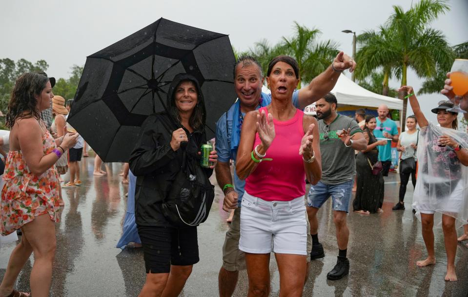 People dance in the rain during the USA Today Wine and Food Experience at Paradise Coast Sports Complex in Naples on Saturday, Sept. 30, 2023.