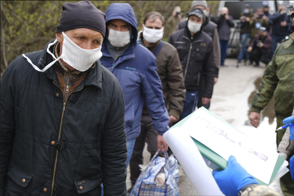 Russia-backed separatists war prisoners wearing masks to protect against coronavirus walk during a prisoner exchange, in Donetsk region, eastern Ukraine, Thursday, April 16, 2020. Ukrainian forces and Russia-backed rebels in eastern Ukraine have begun exchanging prisoners in a move aimed at ending their five-year long war. (Ukrainian Presidential Press Office via AP)