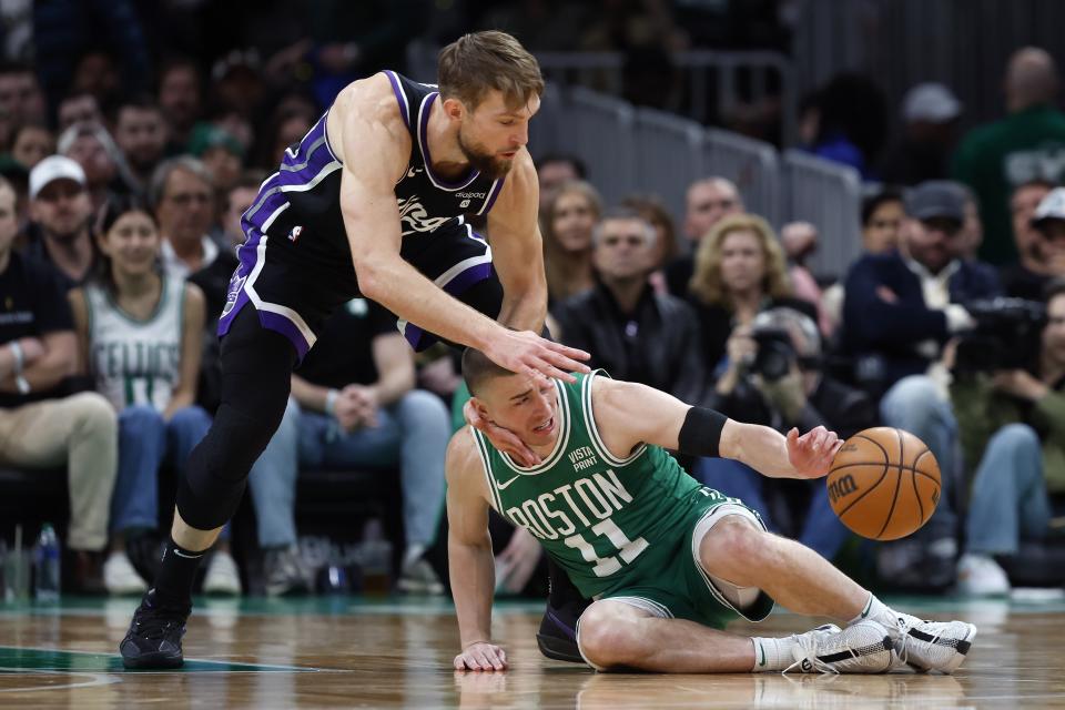 Boston Celtics' Payton Pritchard (11) loses control of the ball next to Sacramento Kings' Domantas Sabonis during the first half of an NBA basketball game Friday, April 5, 2024, in Boston. (AP Photo/Michael Dwyer)