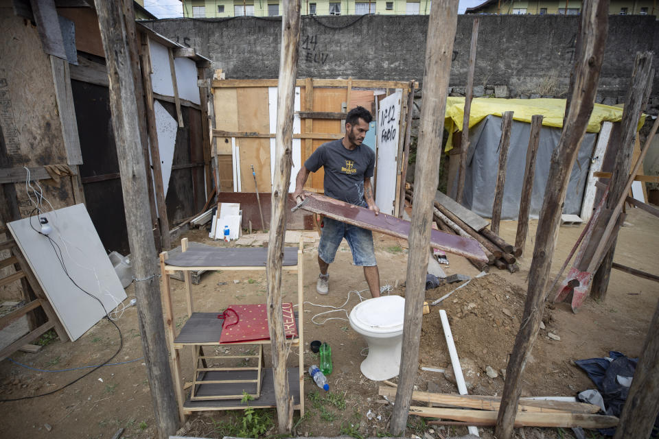 FILE - In this May 15, 2021 file photo, Geovani de Souza, who lost his job as a doorman, works to help a friend build a home in the Penha Brasil favela, where families like his have started relocating during the coronavirus pandemic, in Sao Paulo, Brazil. Geovani de Souza and his pregnant wife were among the 200 families who moved in about six months ago amid the economic turmoil caused by COVID-19. (AP Photo/Andre Penner)