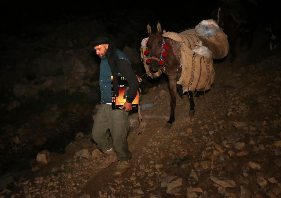 In this picture taken early Sunday, April 20, 2014, Ibrahim Abdulghani, 32, leads his horse with the belongings of Syrian refugees as he descends from the 2,814-meter (9,232-foot) high Mount Hermon (Jabal el-Sheikh), in southeast Lebanon. Abdulghani, from Syria, works as a construction worker during the day in Lebanon and volunteers at night to help Syrians escape. (AP Photo/Hussein Malla)