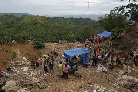 Residents and rescue workers stand at the site of a landslide at a gold mine in San Juan Arriba, on the outskirts of Tegucigalpa July 3, 2014. REUTERS/Jorge Cabrera