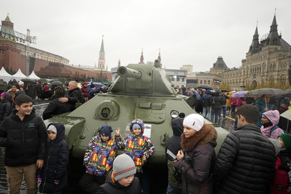 People pose for a photo in front of a Soviet era T-34 tank at an open air interactive museum to commemorate the 82nd anniversary of the World War II-era parade, at Red Square, in Moscow, Russia, on Monday, Nov. 6, 2023. The theatrical performance marks the 82nd anniversary of a World War II historic parade in Red Square and honored the participants in the Nov. 7, 1941 parade who headed directly to the front lines to defend Moscow from the Nazi forces. (AP Photo/Alexander Zemlianichenko)