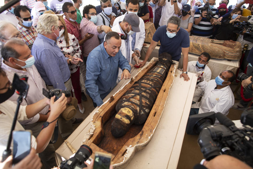 Khaled El-Enaby, Minister of Tourism and Antiquities, right, and Mostafa Waziri, the secretary-general of the Supreme Council of Antiquities, left, react after opening the sarcophagus is around 2500 years old at the Saqqara archaeological site, 30 kilometers (19 miles) south of Cairo, Egypt, Saturday, Oct. 3, 2020. Egypt says archaeologists have unearthed about 60 ancient coffins in a vast necropolis south of Cairo. The Egyptian Tourism and Antiquities Minister says at least 59 sealed sarcophagi with mummies inside were found that had been buried in three wells more than 2,600 years ago. (AP Photo/Mahmoud Khaled)