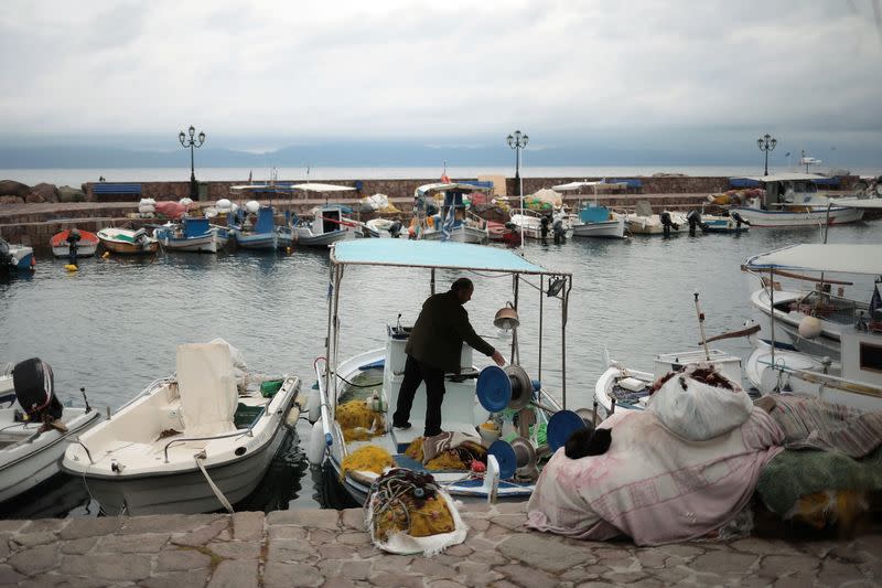 A fisherman works on his boat at the port of the village of Skala Sikamias, on the island of Lesbos