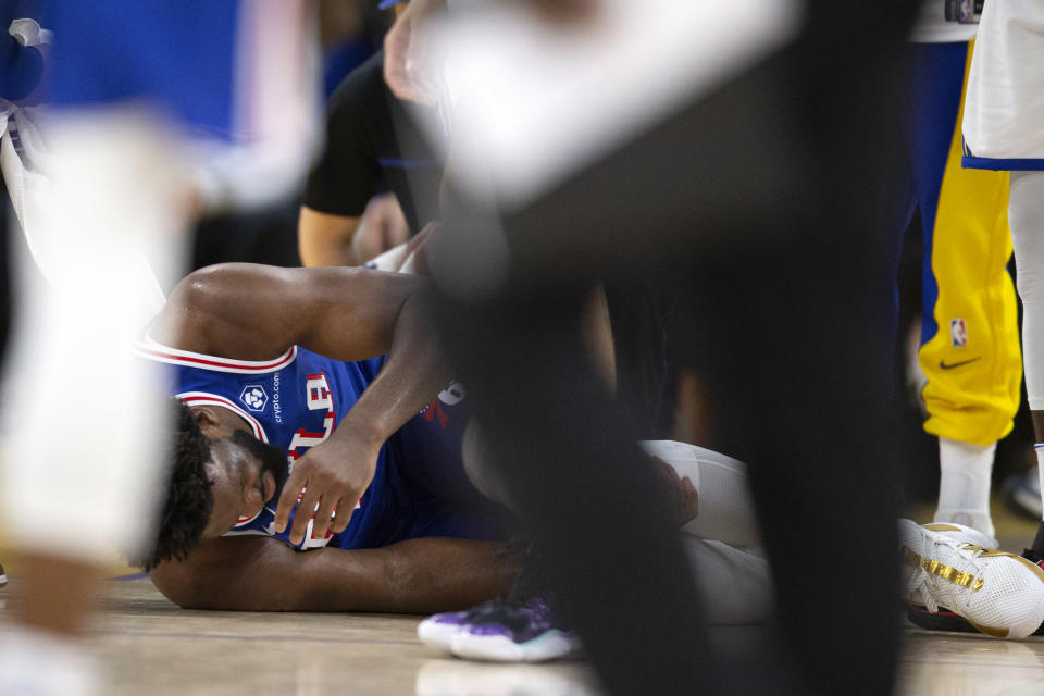 Philadelphia 76ers center Joel Embiid (21) lays on the court in obvious pain after falling pursuing a loose ball against the Golden State Warriors during the second half of an NBA basketball game, Tuesday, Jan. 30, 2024, in San Francisco. Embiid left the game and did not return. (AP Photo/D. Ross Cameron)