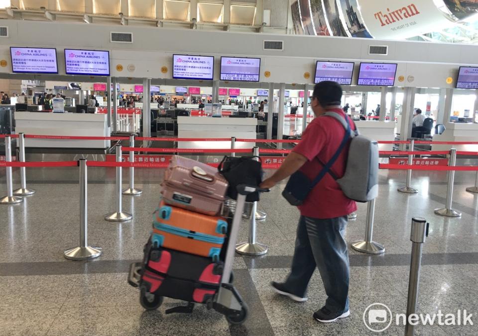 一位將出境旅客推著行李經過高雄小港國際機場華航報到櫃檯。   圖：張良一攝