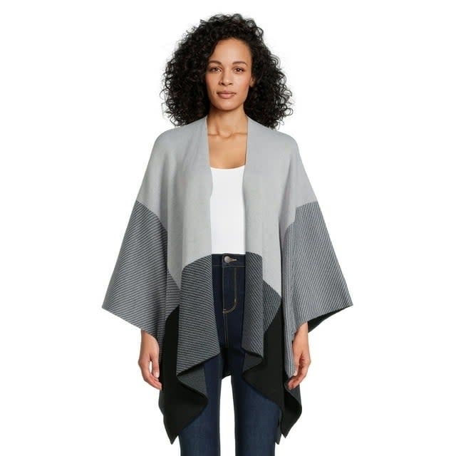 model wearing a draped cape over a white top and jeans