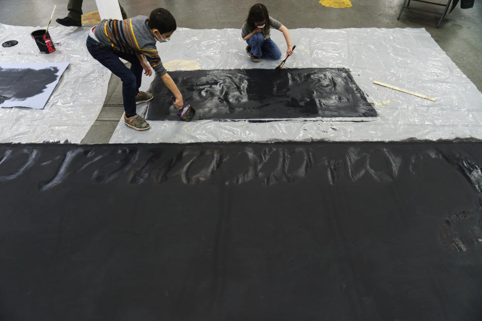 Children supporting the Apache Stronghold group who traveled from Arizona paint protest banners at Self Help Graphics & Art in the Los Angeles neighborhood of Boyle Heights on Monday, March 20, 2023. The Apache group battling a foreign mining firm that wants to build one of the largest copper mines in the United States on what tribal members say is sacred land will get a new chance to make its point Tuesday when a full federal appeals court panel takes another look at the case. (AP Photo/Damian Dovarganes)