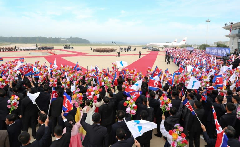 The North's unique brand of choreographed mass adulation was on full display as hundreds of people on the tarmac waved North Korean flags and unification ones depicting an undivided peninsula