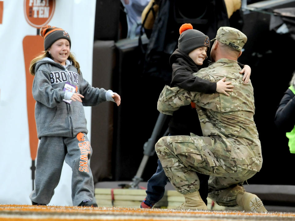 CLEVELAND, OH - DECEMBER 14, 2014: Staff Sargent Anthony Wagner embraces his children after surprising them during a timeout of game between the Cincinnati Bengals and the Cleveland Browns on December 14, 2014 at FirstEnergy Stadium in Cleveland, Ohio. Cincinnati won 30-0. (Photo by Nick Cammett/Diamond Images/Getty Images)  