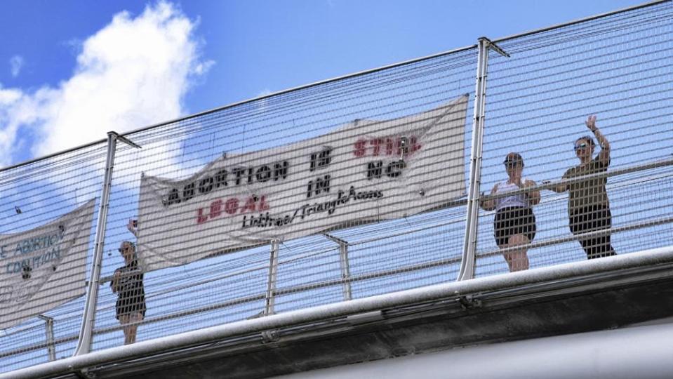 Volunteers with the Triangle Abortion Access Coalition wave to cars passing under the American Tobacco Trail Bridge over Interstate 40 in Durham, N.C., Friday, June 24, 2022, the afternoon that the Supreme Court decision overturning Roe v. Wade was handed down. (Angelina Katsanis/The News & Observer via AP)