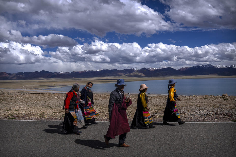 Members of the Buddhist faithful walk along a path to a holy site in Namtso in western China's Tibet Autonomous Region, Wednesday, June 2, 2021, as seen during a government organized visit for foreign journalists. High-pressure tactics employed by China's ruling Communist Party appear to be finding success in separating Tibetans from their traditional Buddhist culture and the influence of the Dalai Lama. (AP Photo/Mark Schiefelbein)