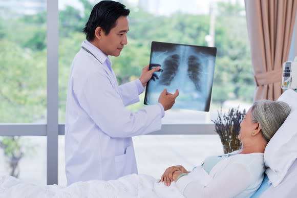 Doctor showing a patient in a bed a chest X-ray
