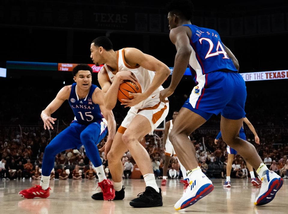 Texas forward Dylan Disu controls the ball against Kansas defenders Kevin McCullar, back, and forward KJ Adams, right, during the Longhorns' 75-59 win in the regular-season finale. One week later, Texas beat Kansas again in the Big 12 Tournament title game.