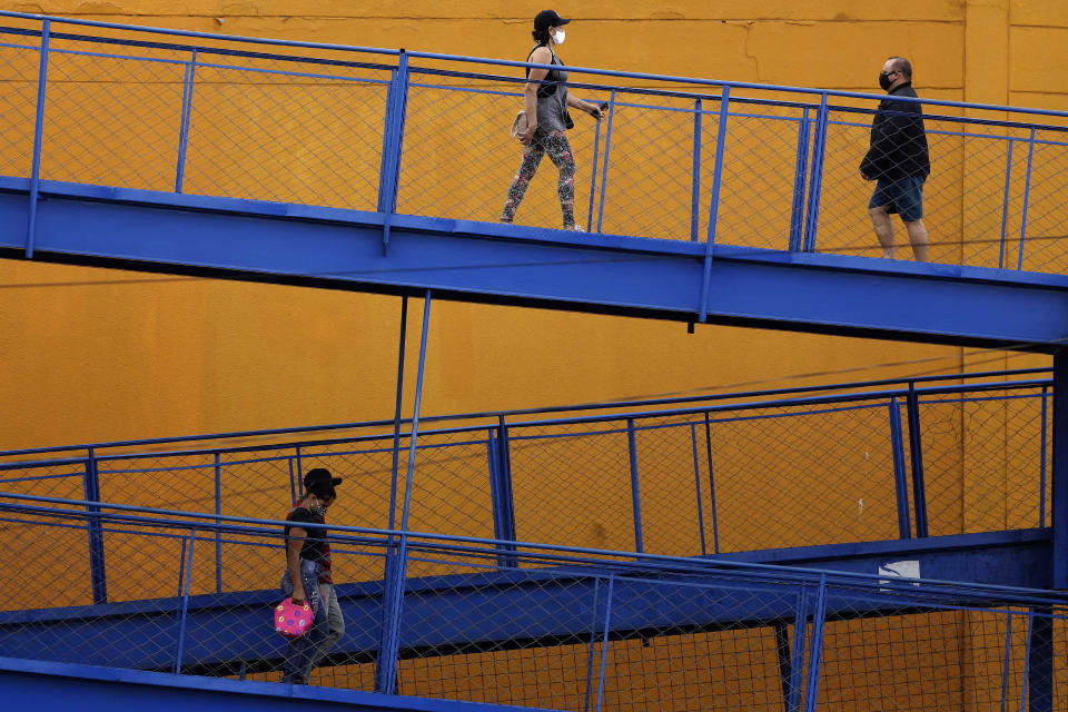 Commuters wearing face masks due to the new coronavirus pandemic walk on a ramp to the public bus system in Valparaiso, Brazil, Wednesday, May 20, 2020. (AP Photo/Eraldo Peres)