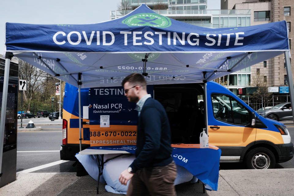 A man with no mask passes a COVID testing site.