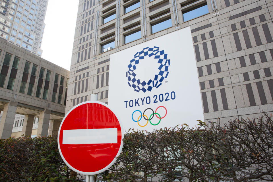 TOKYO, JAPAN - 2020/03/19: A stop sign in front of the Tokyo Metropolitan Government Building while the Tokyo 2020 Olympic Games banner is seen in the background.  Japanese start thinking that it would be the best to postpone the Tokyo 2020 Olympic and Paralympic Games due to the fear of spreading the Covid-19 Coronavirus more into its population. (Photo by Stanislav Kogiku/SOPA Images/LightRocket via Getty Images)