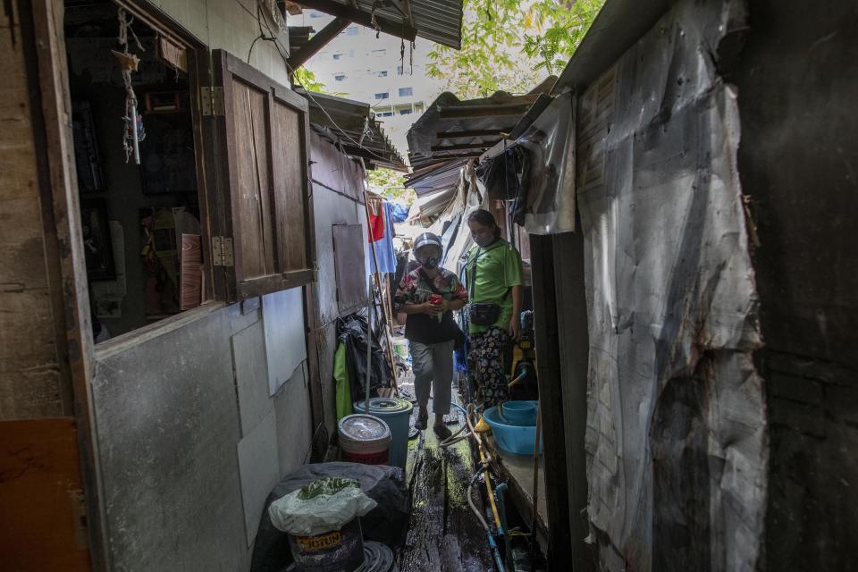 Kanyarat Phuankuntod, left, and Jariya Saekean, teachers of Makkasan preschool, walk in a narrow passage after delivering meals for children in Bangkok, Thailand Wednesday, June 24, 2020. During the third month that schools remained closed due to the coronavirus outbreak, teachers have cooked meals, assembled food parcels and distributed them to families in this community sandwiched between an old railway line and a khlong, one of Bangkok’s urban canals. (AP Photo/Gemunu Amarasinghe)