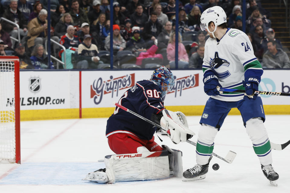 Columbus Blue Jackets' Elvis Merzlikins, left, makes a save against Vancouver Canucks' Pius Suter during the first period of an NHL hockey game Monday, Jan. 15, 2024, in Columbus, Ohio. (AP Photo/Jay LaPrete)