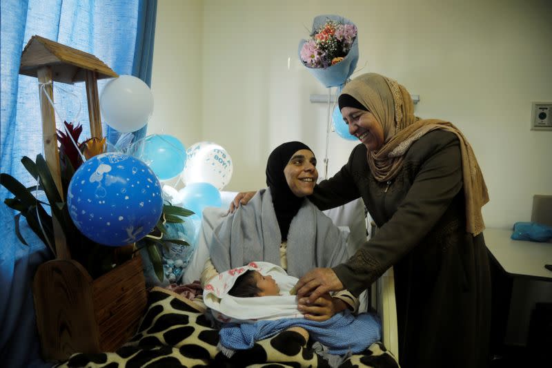 Palestinian woman holds her newborn boy as she smiles with her relative at the Holy Family hospital in Bethlehem in the Israeli-occupied West Bank