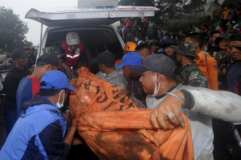 Rescuers carry the body of a victim of the eruption of Mount Marapi into an ambulance in Batu Palano, West Sumatra, Indonesia, Tuesday, Dec. 5, 2023. Rescuers searching the hazardous slopes of the volcano found more bodies of climbers who were caught by a surprise weekend eruption, raising the number of confirmed dead to nearly two dozens, officials said Tuesday. (AP Photo/Ardhy Fernando)