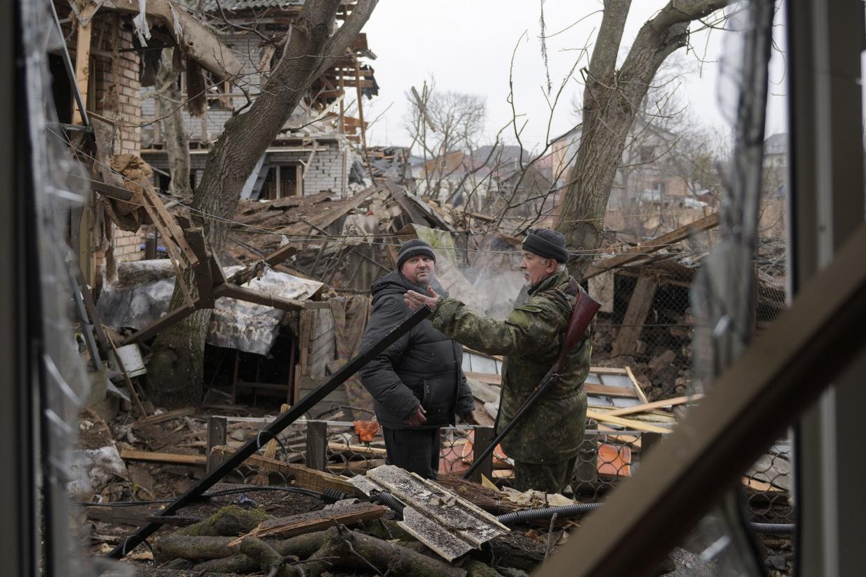 Andrey Goncharuk, 68, right, a member of the territorial defense speaks to a man in the backyard of a house damaged by a Russian airstrike, according to locals, in Gorenka, outside the capital Kyiv, Ukraine, Wednesday, March 2, 2022.