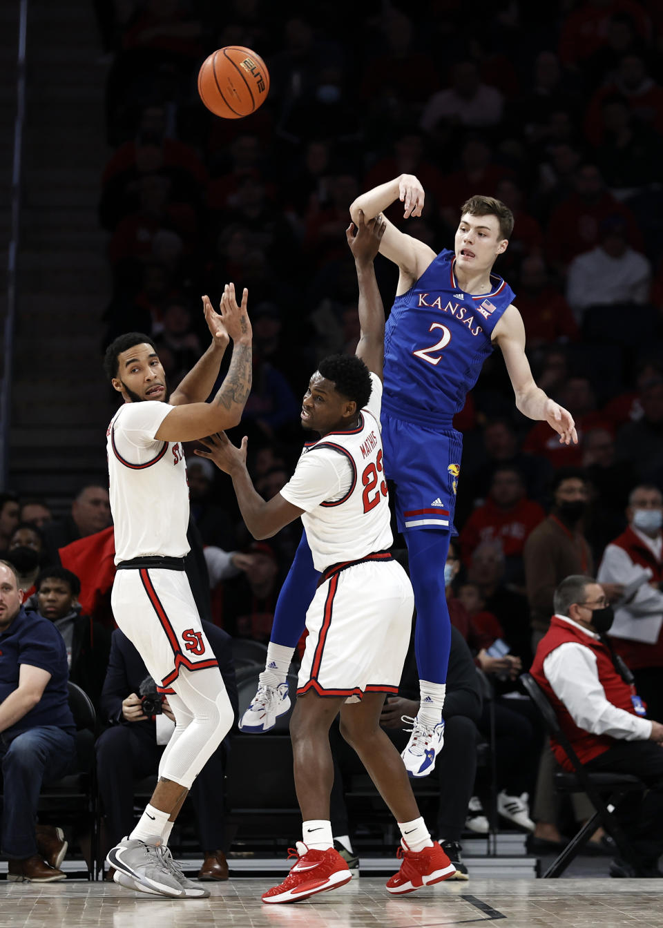 Kansas guard Christian Braun (2) passes the ball over St. John's guard Montez Mathis during the first half of an NCAA college basketball game Friday, Dec. 3, 2021, in Elmont, N.Y. (AP Photo/Adam Hunger)