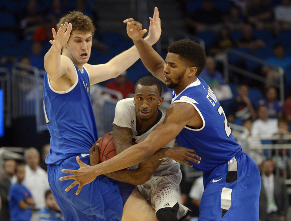 FILE - In this March 22, 2014 file photo, Louisville guard Russ Smith, center, attempts to dribble between Saint Louis forwards Rob Loe, left, and Dwayne Evans during the second half in a third-round game in the NCAA college basketball tournament in Orlando, Fla. Smith was selected to The Associated Press All-America team, released Monday, March 31, 2014. (AP Photo/Phelan M. Ebenhack, File)