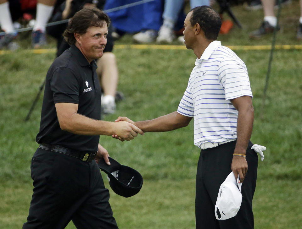 FILE - In this Aug. 8, 2014, file photo, Phil Mickelson, left, shakes hands with Tiger Wood after the second round of the PGA Championship golf tournament at Valhalla Golf Club in Louisville, Ky. Woods and Mickelson play pay-per-view exhibition Friday in Las Vegas. (AP Photo/David J. Phillip, File)