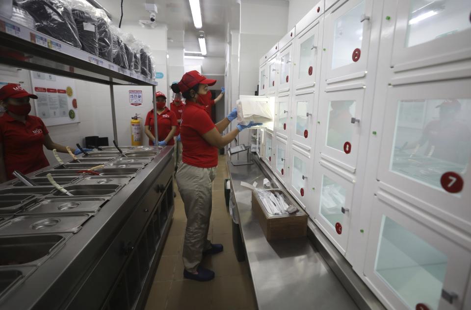 An employee places a food order into a two-way locker that is then retrieved by the customer on the other end at a MUY restaurant, a Colombian fast food chain that is planning to turn its branches into automated restaurants, in Bogota, Colombia, Thursday, Aug. 13, 2020. The chain has opened its first “contactless store” in a commercial district of Bogota, where many restaurants have been forced to shut down because of a ban on sit-down dining. (AP Photo/Fernando Vergara) MUY restaurant server places prepared food for a client in a locker at on the chain's locations in Bogota, Colombia, Thursday, Aug. 13, 2020. MUY restaurant has devised an eatery where the customer never has to deal with restaurant staff. The entire operation is automated and people-free when it comes to ordering and taking delivery of your food. (AP Photo/Fernando Vergara)