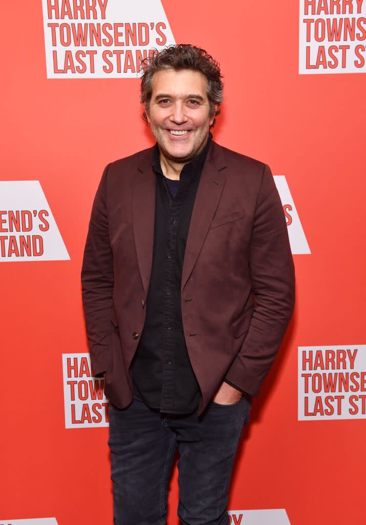 Craig in a casual blazer and shirt posing with hands in pockets at an event