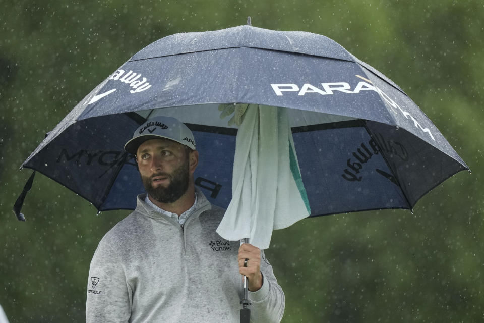Jon Rahm, of Spain, waits to play in the rain on the 18th hole during the weather delayed second round of the Masters golf tournament at Augusta National Golf Club on Saturday, April 8, 2023, in Augusta, Ga. (AP Photo/Charlie Riedel)
