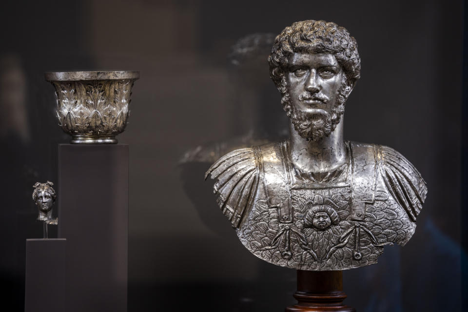 A silver bust of Lucius Verus is on display with a decorative element in the shape of a capital and a head of a woman, all part of the so called Treasure of Marengo, at the exhibition 'Between us and the ancients. The instant and eternity' in Rome's Diocletian Baths, Wednesday, May 3, 2023. The exhibition will open to the public from May 4 through July 30, 2023. (AP Photo/Domenico Stinellis)