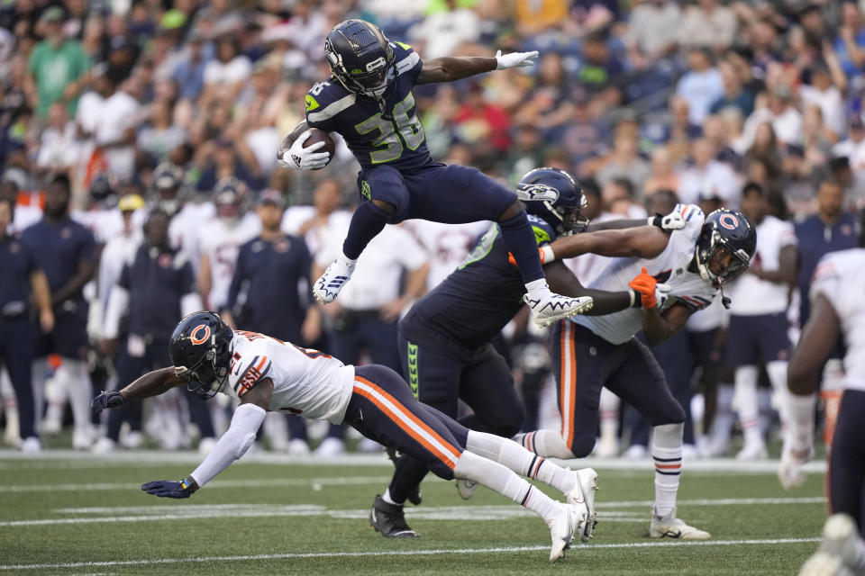 Seattle Seahawks running back Darwin Thompson (36) leaps over Chicago Bears safety A.J. Thomas during the second half of a preseason NFL football game, Thursday, Aug. 18, 2022, in Seattle. (AP Photo/Stephen Brashear)