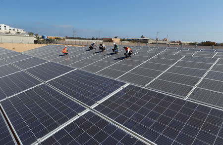 Palestinian workers install solar panels at Khan Younis Waste Water Treatment Plant, in the southern Gaza Strip July 31, 2018. REUTERS/Ibraheem Abu Mustafa