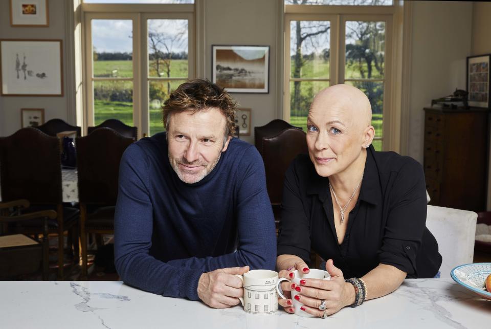 Pictured: Sarah Beeny and Graham Swift in their kitchen sitting on stools drinking tea/coffee - Sarah Beeny Vs Cancer (Channel 4)