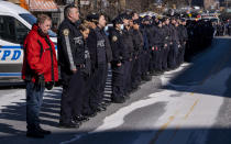 Police officers stand at attention after the remains of New York City Police Department Officer Wilbert Mora arrived at a funeral home in the Manhattan borough of New York, Wednesday, Jan. 26, 2022. Officer Mora, who died Tuesday, was gravely wounded last week in a Harlem shooting that also killed his partner. (AP Photo/Craig Ruttle)