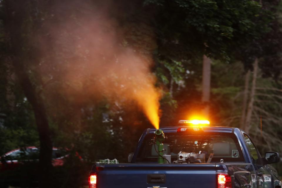 A crew from the East Middlesex Mosquito Control Project spray to control mosquitos from a pick-up truck on Wednesday, July 8, 2020, while driving through a neighborhood in Burlington, Mass. Officials are preparing for another summer with a high number of cases of eastern equine encephalitis, a rare but severe neurological illness transmitted by mosquitoes that hit the state particularly hard last summer. (AP Photo/Charles Krupa)