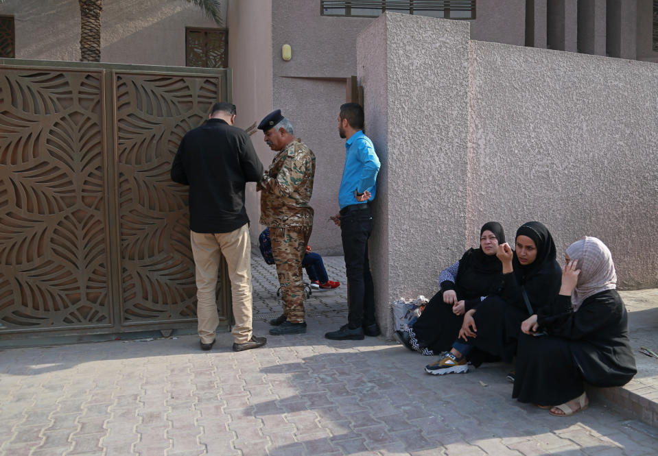 A policeman stands guard at the door while parents wait for their children, outside a school in Baghdad, Iraq, Monday, Nov. 1, 2021. Across Iraq, students returned to classrooms Monday for the first time in a year and a half – a stoppage caused by the coronavirus pandemic - amid overcrowding and confusion about COVID-19 safety measures. (AP Photo/Hadi Mizban)